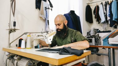 İşyerindeki dikiş atölyesinde terzi. Stüdyosu Sunny 'dir. Renkli kumaşlar, giysiler görünür..