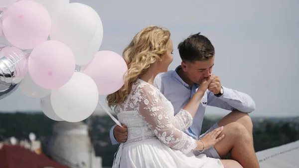 Pareja joven sentada en el techo con globos. —  Fotos de Stock