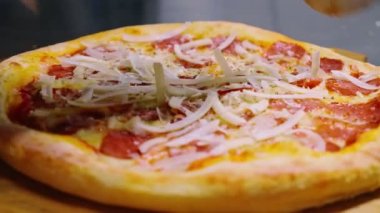 Yakın plan. Şef güzel bir salam ve peynirli pizza dilimliyor. Geleneksel İtalyan yemeği. Geleneksel İtalyan Restoranı.