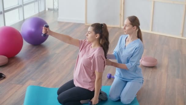 Seorang wanita hamil muda melakukan Latihan dengan seorang pekerja kesehatan di Klinik. — Stok Video