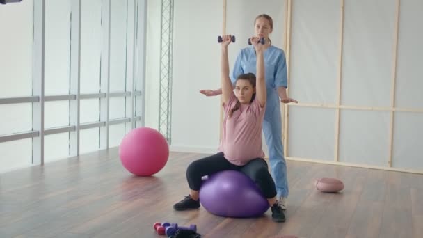 Orvosi dolgozó Segítő Terhes nő csinálni labda gyakorlatok — Stock videók
