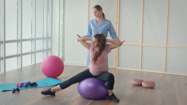 Ärztin hilft schwangerer Frau bei Ballübungen — Stockvideo