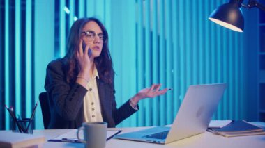 Modern Ofiste Geç Saatlere Kadar Çalışan, Telefonda Konuşan Yorgun ve Sinirli Bir İş Kadını. İş yeri stresi, ofis yorgunluğu ve geç saatlere kadar çalışma baskısı ve hüsranı kavramı
