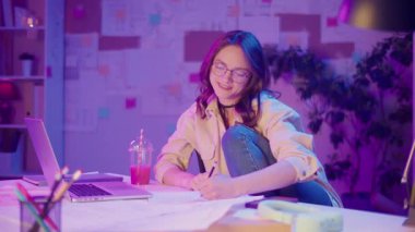 Güçlendirilmiş Öğrenme, Akademik Özgüven, Dijital Çağ. Öğrenci rahat poz verip Neon Room 'daki kameraya bakar. Odaklanma, Odaklanma ve Eğitimin Yeni Yüzü