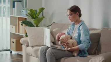 Uzaktan Çalışma, Ebeveynlik Mücadelesi, Duygusal Yükleme. Profesyonel bir kadın ağlayan bebeğini kucağında tutarken dizüstü bilgisayar görevlerine odaklanmaya çalışır, Modern Ebeveynliğin ve Dijital Kariyerin Günlük Zorluklarını Gösterir