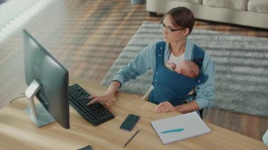 Çalışmanın Geleceği Yeni Çalışma Kültürü. Genç anne, bebek taşırken, modern ebeveynlik ve kariyer entegrasyonunu gösterirken İçişleri Bakanlığı 'nda bilgisayar kullanıyor.