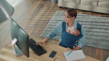 Çalışmanın Geleceği Yeni Çalışma Kültürü. Genç anne, bebek taşırken, modern ebeveynlik ve kariyer entegrasyonunu gösterirken İçişleri Bakanlığı 'nda bilgisayar kullanıyor.