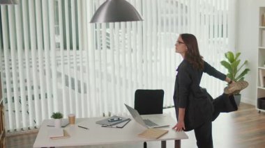 Stres atağı ve çalışanların refahı. Ofis Yöneticisi, Ağrıyı Önlemek, Duruşu İyileştirmek, Çalışmaya Denge Eklemek ve Sağlıklı İş Yeri 'ni Desteklemek İçin, Masada Ayakta Dörtlü ve Belkemiği Esnetme Uygulamasını Yapıyor