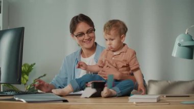 Aile dostu iş yeri. Genç Anne Kucağında Yürüyen Çocukla Uzaktan Çalışmayı Dengeleyerek, Ebeveynlerin Belirleyici ve Destekleyici İş Kültürünü Vurguluyor