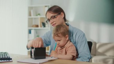 Yaşam Tarzından Herhangi Bir Yerde Çalış. Genç Anne, Çocuğa kucak açarken, Aile Dostunu Gösterirken Ofis Masasında Çalışmaya Çalışıyor