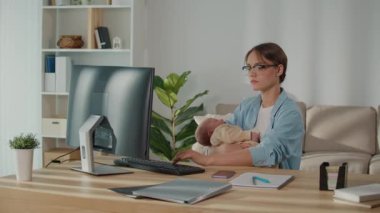 Melez Ebeveynlik, Dijital İş Gücü, Aile Kurumu. Profesyonel Bir Kadın, Uyuyan Bebeği Tutarken, Modern Ebeveynlik, Esneklik ve Evrimleşen İş Kültürü Gösterirken Ofis Bilgisayarında Çalışıyor