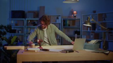 Garaj atölyesinde dizüstü bilgisayarla ahşap kalasları ölçen adam. Marangozluk, Ev Yenileme, DIY Projeleri, Ahşap Planlama ve Modern Yaratıcı Çalışma Alanı Konsepti.