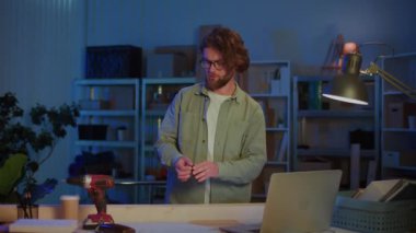 Garaj atölyesinde dizüstü bilgisayarla ahşap kalasları ölçen adam. Marangozluk, Ev Yenileme, DIY Projeleri, Ahşap Planlama ve Modern Yaratıcı Çalışma Alanı Konsepti.