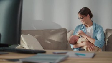 Uzaktan Çalışma, Modern Ebeveynlik, Hibrit Yaşam Tarzı. Profesyonel bir kadın bebeğini kucağında tutarken evden çalışır, etrafı ofis aletleriyle çevrilidir. Esneklik Sahnesi, Aile Katılımı ve Dijital İş Gücü