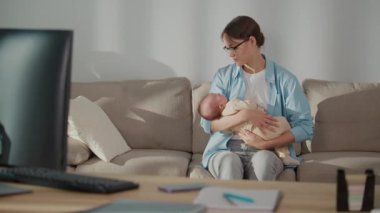 Uzaktan Çalışma, Modern Ebeveynlik, Hibrit Yaşam Tarzı. Profesyonel bir kadın bebeğini kucağında tutarken evden çalışır, etrafı ofis aletleriyle çevrilidir. Bir Esneklik Sahnesi Aile Edinimi ve Dijital İş Gücü