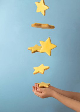 Çocuk elleri mavi arka planda sarı zencefilli kurabiye yıldızlarını yakalar. Tatlı rüyalar konsepti.