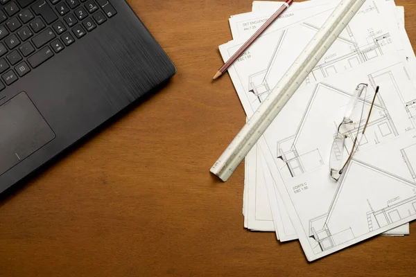 Construction plan, drawing elements and notebook on wooden table