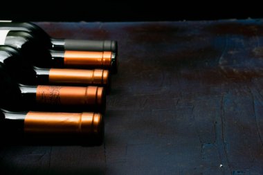 Şarap şişelerinin üstü koyu arkaplanda dikiliyor.