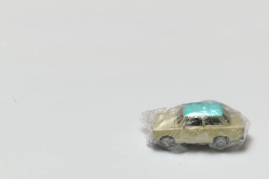 Sağında baloncuk olan koruyucu plastik bir filme sarılı minyatür bir araba.