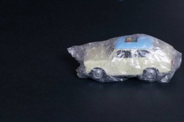 Oyuncak araba siyah bir arkaplanda baloncuk ambalajına sarılı.