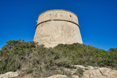 IBIZA, İSPAIN, Mart 2021, İspanyol adası kıyısındaki yuvarlak taş kule savunma duvarı.
