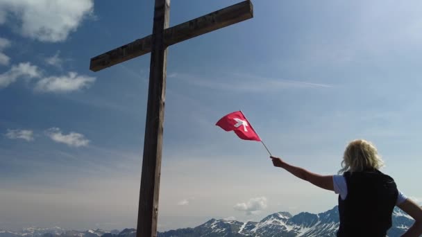 Kvinna ovanpå Piz Scalottas schweiziska flagga — Stockvideo