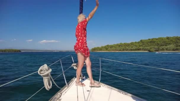 Woman waving hello greeting on bow of a sailboat — Stock Video
