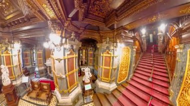 Transilvanya, Romanya - 25 Ağustos 2025: Peles Kalesi büyük merdiven Süslü koyu ahşap oymalar, kırmızı halı koşucusu ve varlıklı tarihi mimari ayrıntılar