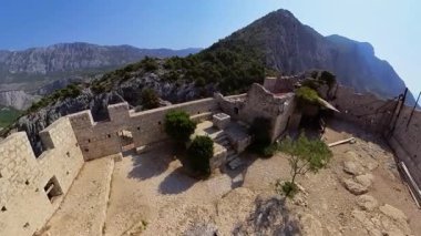 Starigrad kalesi, Hırvatistan 'da bir Hırvat bayrağını dalgalandıran açık gökyüzünün altında büyüleyici Omis kasabası ve engin mavi Adriyatik Denizi' ne bakan bir dağın tepesinde duruyor.