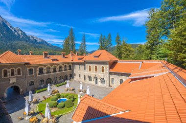 Merkezi avlu, açık hava oturma yerleri, yeşil çalılar, çeşmeler, Romanya 'nın Bucegi Dağları ve Transilvanya ile çevrili Cantacuzino Kalesi kompleksinin havadan görünüşü