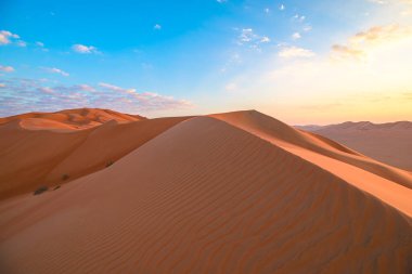 Muazzam çöl manzarası dalgalı dokularla dolu devasa kum tepelerini, güneşin doğuşunun ya da batışının sıcacık ışığında yıkanmış, Zufar 'da yalnızlık ve doğal bir ihtişam hissi yaratıyor, Umman.