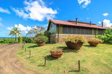 Martinique, Fransız Antilleri - 26 Aralık 2025, 1710 Rhum Agricole damıtma tesisi verandası tropikal bitki örtüsü, beyaz kepenkler ve yeşil ahşap bir ev cephesi ile kaplı