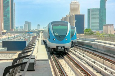 Dubai metro treni yükseltilmiş demiryolu sisteminde seyahat eder, Dubai şehir merkezinin modern şehir manzarası boyunca toplu taşıma hizmeti sunar, yükselen gökdelenleri ve Birleşik Arap Emirlikleri 'nde işlek yolları vardır.