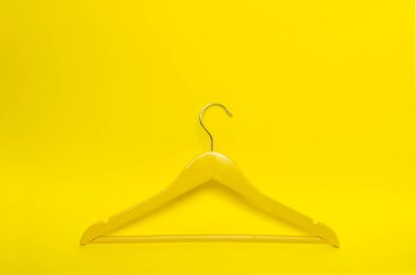 Havada süzülen sarı ahşap askı. Kopyalama alanı olan sarı arkaplan