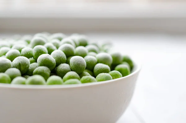 Verse bevroren erwten in een witte kom. met kopieerruimte — Stockfoto