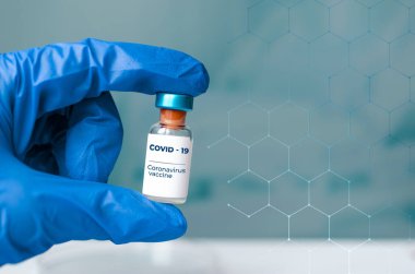 Ampuller elinde ve şırıngada Covid-19 aşısı laboratuvar masasında. Koronavirüs enfeksiyonunun önlenmesi, aşılanması ve tedavisi için. Bulaşıcı tıp konsepti. Kopyalama alanı ile