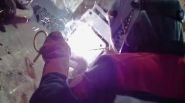 close-up, a worker in a mask of a welder with a drawing at a factory welds a pipe, sparks fly, slow-mo