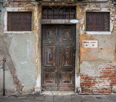 Eski ahşap bir kapı ve paslı bir pencere Venedik, İtalya 'da küçük bir meydanda ızgara yapıyor.