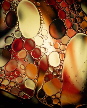 Su yüzeyindeki yağ damlası kabarcıkları, turuncu ve sarı yumuşak arkaplanlı soyuttur.