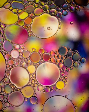 Su yüzeyindeki yağ damlası baloncukları soyut ve çok renkli şeker arkaplanı var.