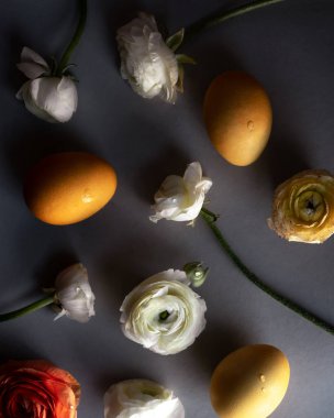 Beyaz, kırmızı ve sarı çiçekler ve gri arkaplanda sarı yumurtalar.