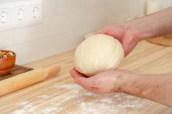 Faceless man kneading dough on kitchen table at home, apartment, flour, scales