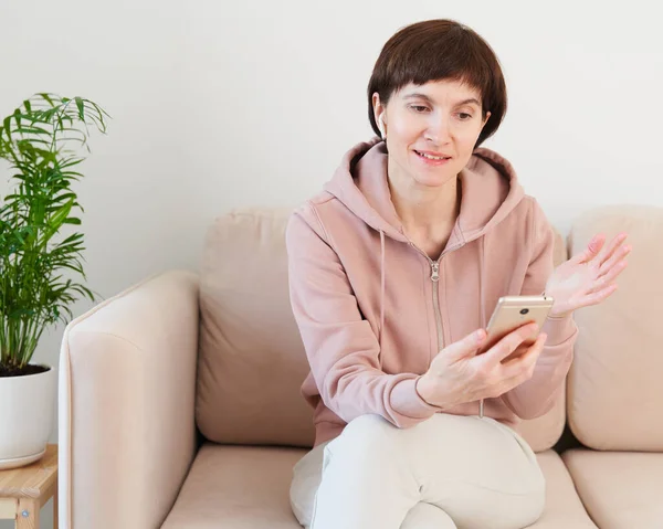 Mature woman recording audio message, speaking to microphone of mobile phone. Middle-aged female