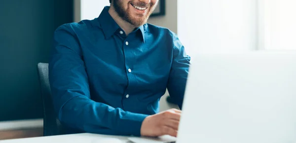 Faceless happy young male office employee working on laptop computer