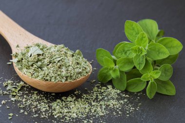 Siyah arka planda kurutulmuş marjoram, taze mercanotu yaprakları, yakın plan.