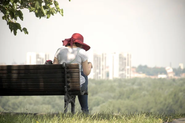 Mulher com chapéu vermelho sentado em um banco, Belgrado — Fotografia de Stock