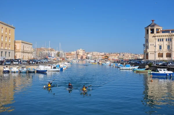 Fishing boats and kayakers in the darsena of Ortigia Islet from the Bridge Umbertino. On the background the skyline of Siracusa on the mainland — Stock Photo, Image