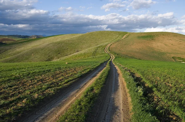 Estrada da sujeira que conduz no alto da colina — Fotografia de Stock