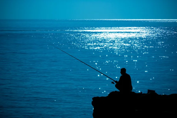 Silhouette man fishing in sea glittering — Stock fotografie
