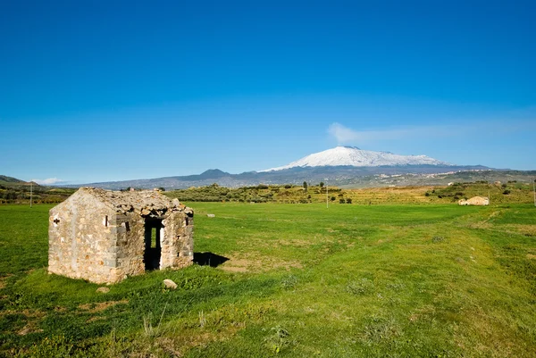 House abandoned in green field, on background volcano Etna — Stock Photo, Image
